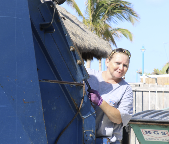 Talking trash – Meet Marathon’s first garbage lady - A man riding on the back of a truck - Garbage truck