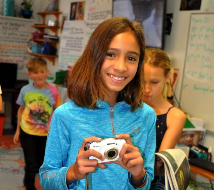 Kids & Media – Treasure Village/Ocean Studies students expand media outreach - A person holding a cell phone - Room
