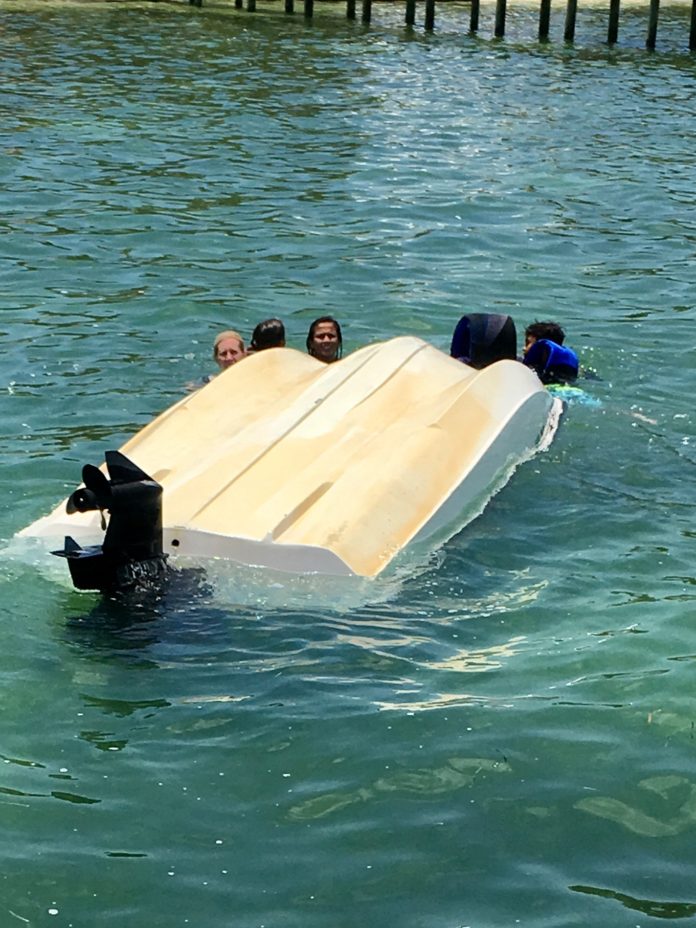 Local rescues 5 children from capsized boat - A group of people swimming in the water - Florida Keys