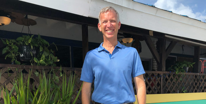 Charles “Chuck” Licis works  tirelessly for Take Stock - A man in a blue shirt standing in front of a building - Florida Keys