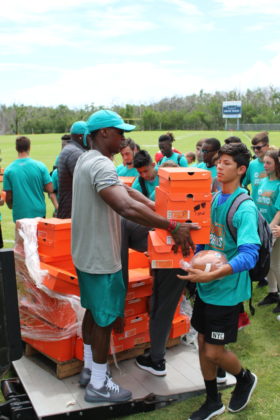 Dolphins to Dolphins – NFL foundation makes huge donation to MHS - A group of people that are standing in the grass - Team sport