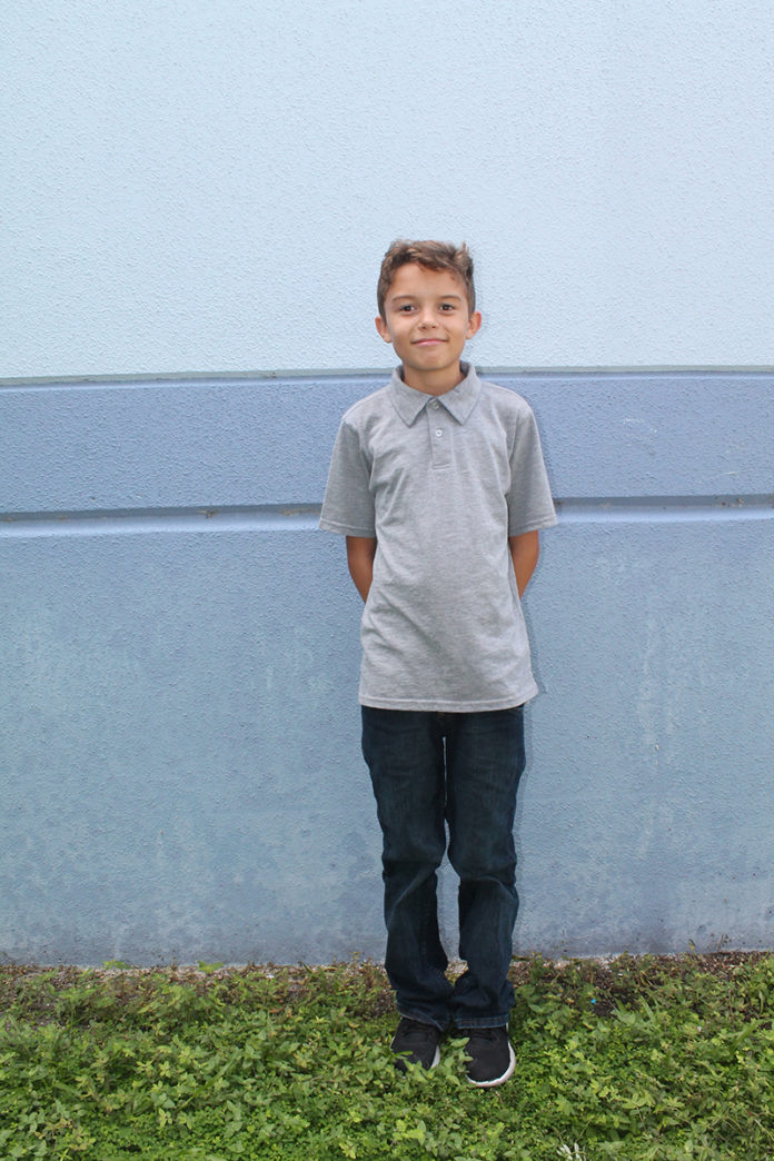 A young boy standing in front of a building - T-shirt