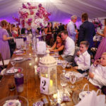 Purple Pumpkin Gala - A group of people sitting at a table in a restaurant - Wedding reception