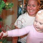 Zonta Club hosts annual event - A person holding a plant in front of a christmas tree - Christmas tree
