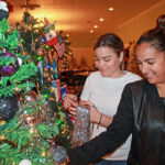 Zonta Club hosts annual event - A group of people standing around a table - Christmas tree