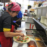 Hot pizza, saucy wings at Key Largo pizzeria - A person preparing food in a kitchen - Pizza