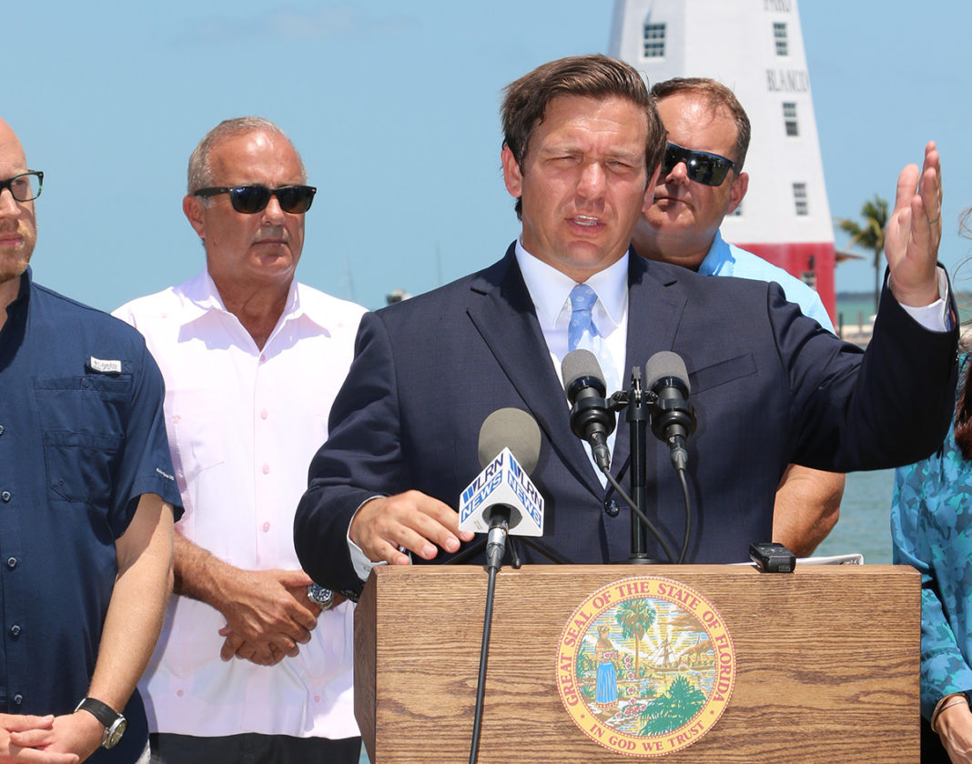 Governor makes first official visit to the Keys - A group of people standing next to a man in a suit and tie - Ron DeSantis
