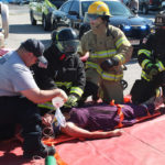 EMS and LEOs stage car accident before prom weekend - A group of people sitting around a car - Firefighter