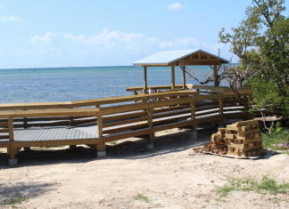 Anne’s Beach reopens following damage sustained from Irma - A wooden bench sitting on top of a sandy beach - Anne's Beach