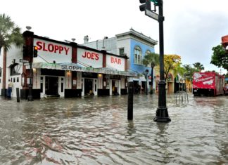 What FEMA flood maps mean for residents, real estate - A group of people walking down a street next to water - Sloppy Joe's Bar