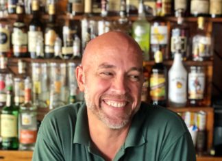 Bushey reflects on Key West, 20 years at Rick’s - A man sitting at a table with wine glasses - Bartender