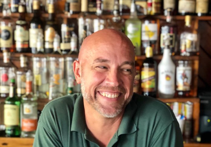 Bushey reflects on Key West, 20 years at Rick’s - A man sitting at a table with wine glasses - Bartender