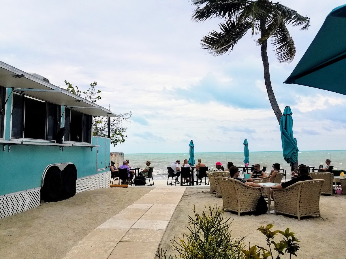 OFF THE PATH KEY – WEST’S SOUTHERNMOST HOUSE IS MORE THAN A MANSION - A group of people sitting at a bus stop - Palm trees