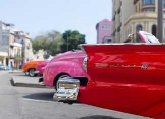 Learn about how to travel to Cuba at Marathon Library talk - A red car parked on the side of a road - Vintage car