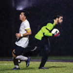 Coral Shores goalie Josh Prince scoops the ball up as a Keys Gate attacker closes in.