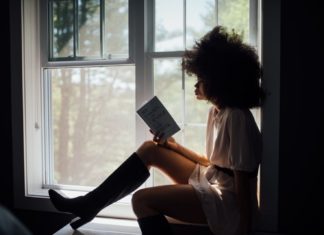 woman sitting on window reading book