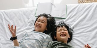 happy ethnic children lying on bed