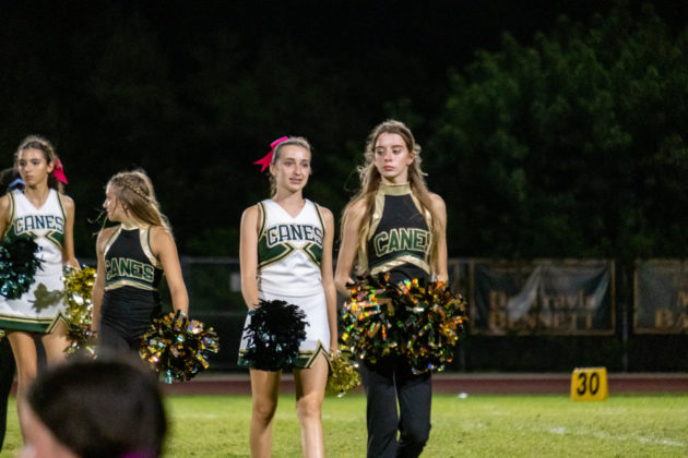 a group of cheerleaders standing on top of a field