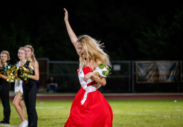 a woman in a red dress is throwing a bouquet