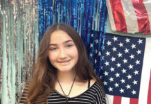 a girl standing in front of a wall with american flags