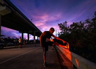 a man standing on the side of a road holding onto a skateboard
