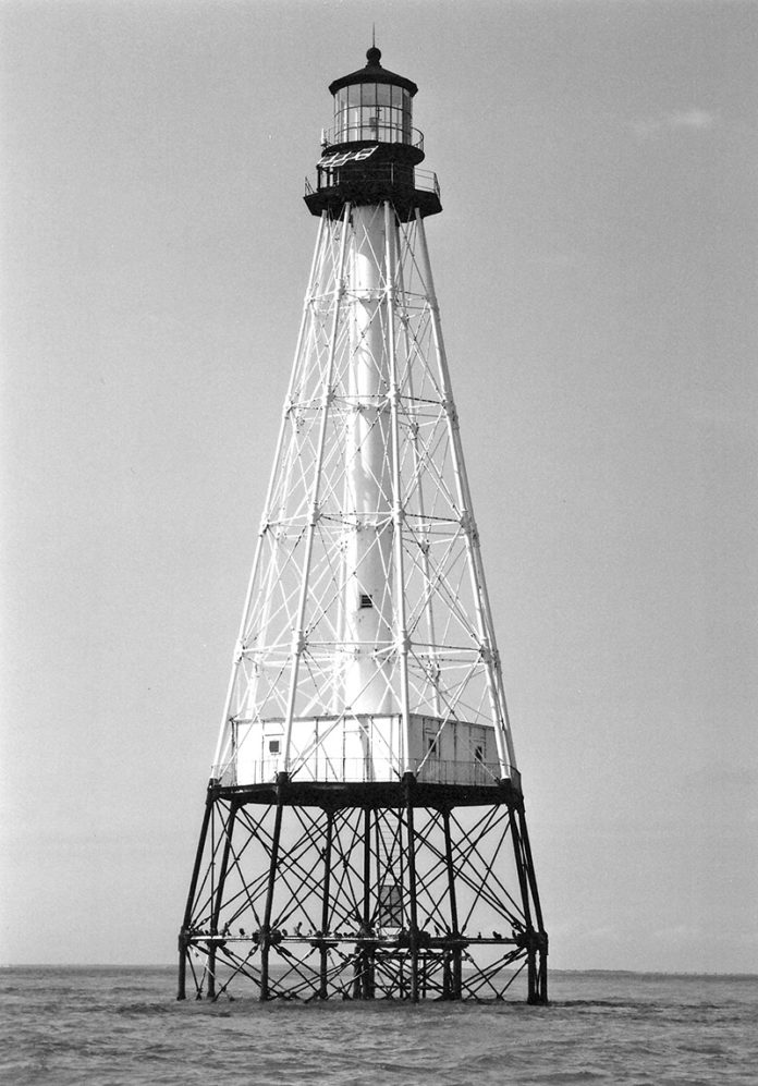 a black and white photo of a lighthouse in the ocean