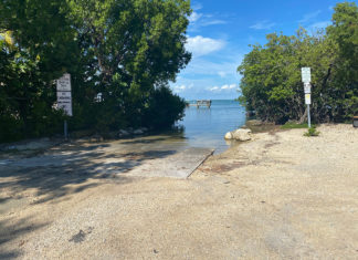 FORSTER MEMORIAL PARK: LOCAL FAVORITE GETS NAMED AFTER THE LATE COUNTY COMMISSIONER a beach with trees and a sign in the foreground