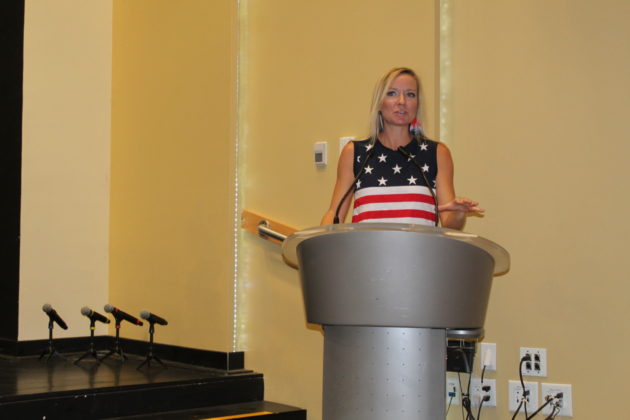 a woman standing at a podium in front of microphones