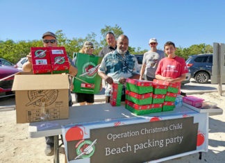 a group of people standing around a table with boxes on it