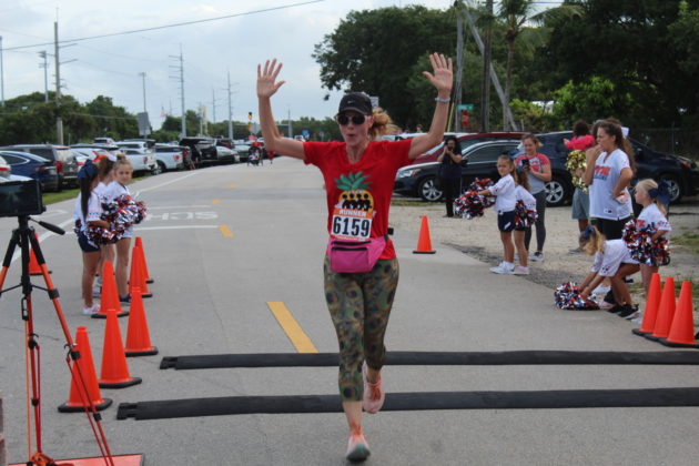 a woman running in a race with her arms in the air