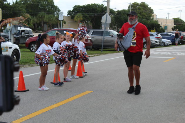 a man walking down the street with a group of cheerleaders