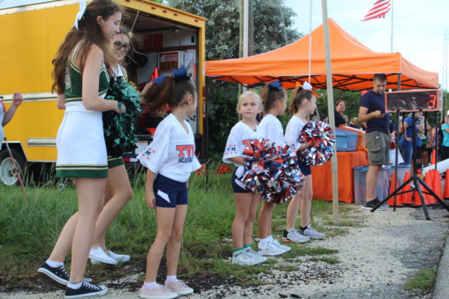 a group of cheerleaders standing in front of a food truck