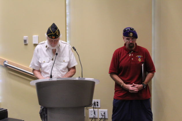 two men standing at a podium in front of a microphone