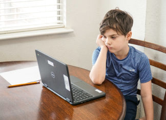 a young boy sitting at a table with a laptop