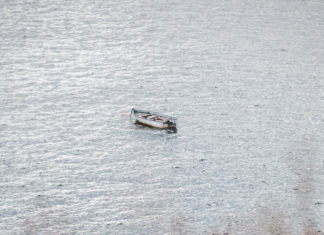 EXPERT ADVICE: UNTIE NOW & TOW LATER a small boat floating on top of a body of water