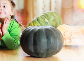 a little girl sitting at a table with a pumpkin