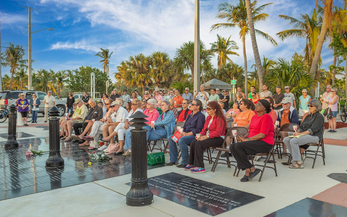 a group of people sitting on top of a sidewalk