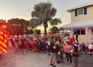 IN PICTURES: SANTA’S VISIT TO COLDWELL BANKER SCHMITT DRAWS CROWD a group of people standing around a fire truck