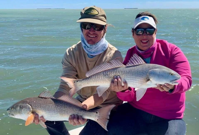 Redbone-1 a couple of people that are holding some fish