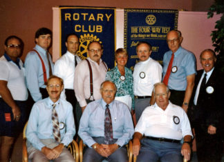 “GRIND, GIVE, REPEAT”: MARATHON ROTARY CLUB CELEBRATES 60 YEARS a group of men standing and sitting in front of a rotary club sign