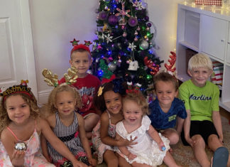 a group of children sitting in front of a christmas tree