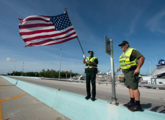 a couple of men standing next to a flag