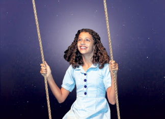 ‘MATILDA’ MAKES MAGIC AT WATERFRONT PLAYHOUSE a woman in a blue dress is sitting on a swing