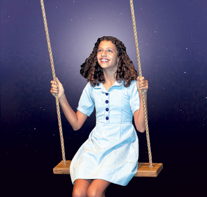 a woman in a blue dress is sitting on a swing