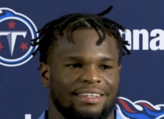 a man with dreadlocks standing in front of a wall