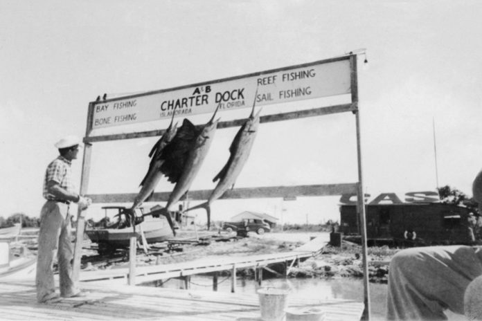 a black and white photo of a man standing next to a sign
