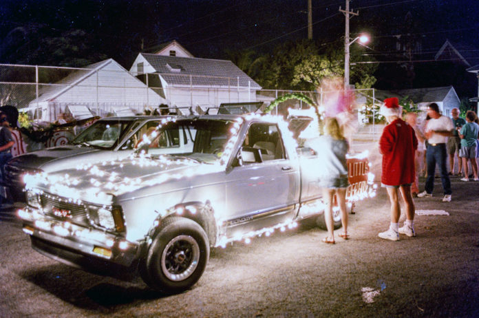a group of people standing around a car with lights on it