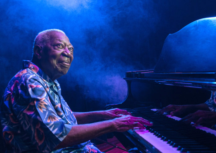 a man sitting at a piano in front of a blue light