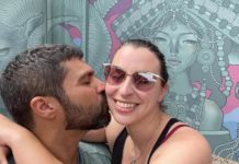 a man and a woman kissing in front of a mural