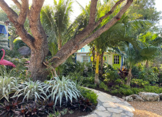 ISLAND VIBES: PROPERTY OWNERS INTERPRET KEYS STYLE ON GARDEN WALK a garden with a flamingo statue in the middle of it